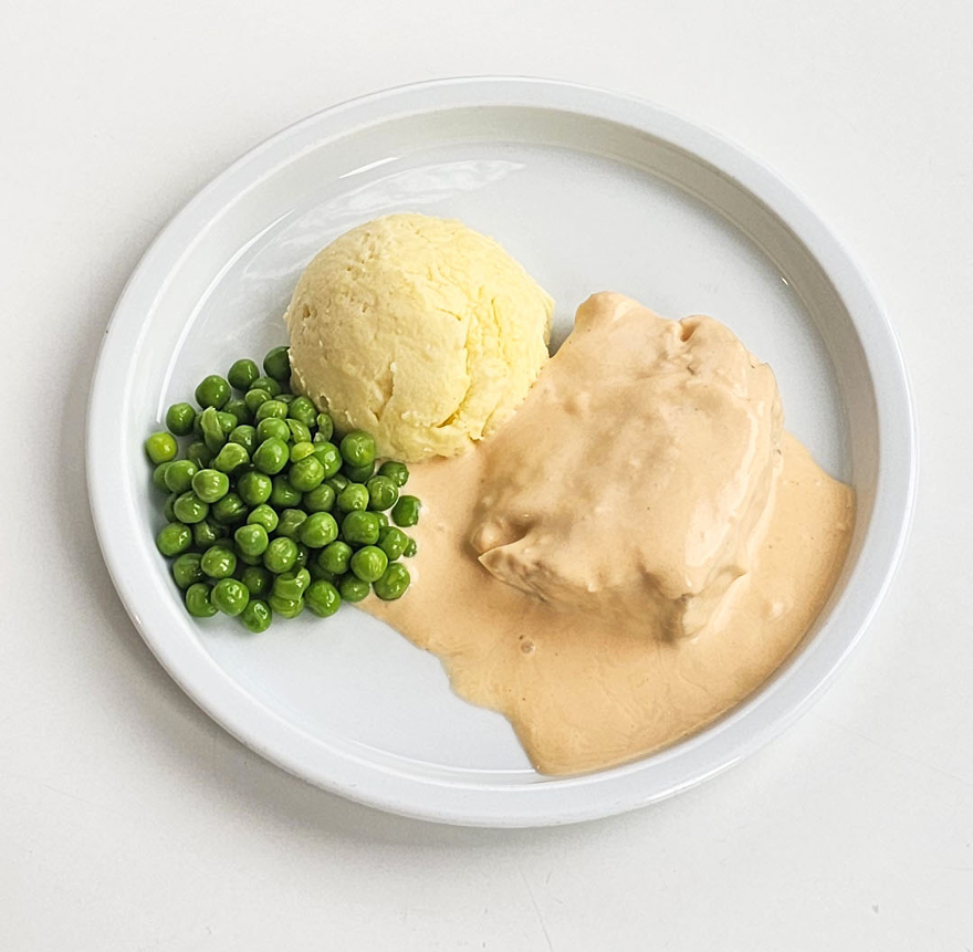 Fisk i hummersås med potatismos och ärtor på en tallrik