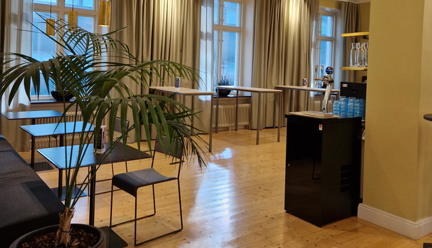 Fikayta med soffa och tillhörande bord samt högre ståbord och en vattenmaskin.