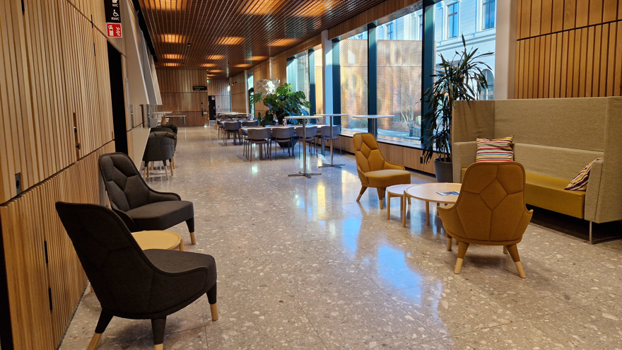 Fikayta med en soffa och några grupper med fåtöljer och tillhörande lägre bord, några ståbord och vanliga matbord och stolar.