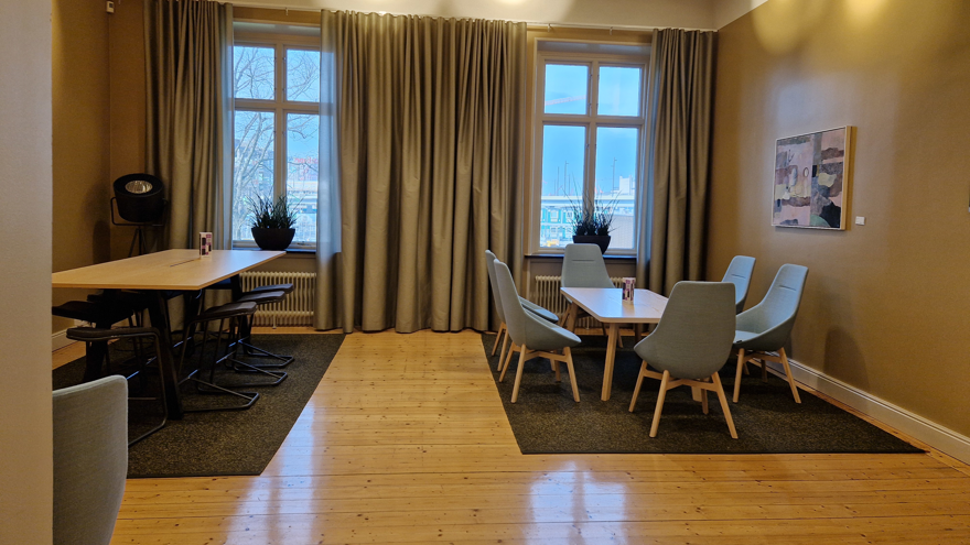 Ett större bord med tillhörande pallar och en grupp med blåa fåtöljer och ett bord.